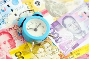 Philippines peso currency money bills and alarm clock. The concept of time management and income