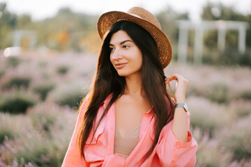Young woman enjoys a sunny day in lavender field with a straw hat and vibrant shirt