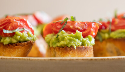 avocado crostini topped with roasted cherry tomatoes and fresh basil, served as a bite-sized party appetizer. Perfect for food blogs, entertaining ideas