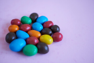 Colorful chocolate candies on pink background. Selective focus.