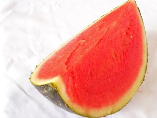 A large piece of ripe bright red watermelon on a white background. The juicy flesh and green rind...