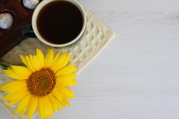 a box of chocolates with a cup of coffee and a small sunflower early in the morning