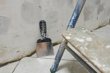 Trowel and ladder on the floor in the construction site.