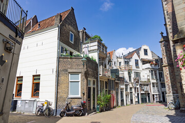 A row of classic Dutch townhouses with different facades line a cobblestone street in a historic...