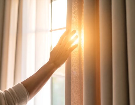 Hand gently opens curtains, sunlight streams through, illuminating the scene