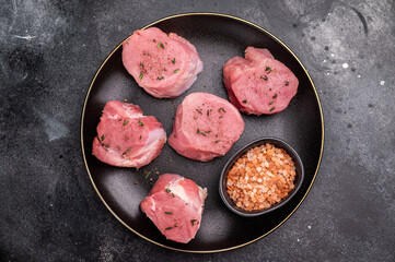 Tender fresh pork medallion, raw tenderloin meat perfect for elevating your dinner table with a touch of culinary finesse. black background. top view