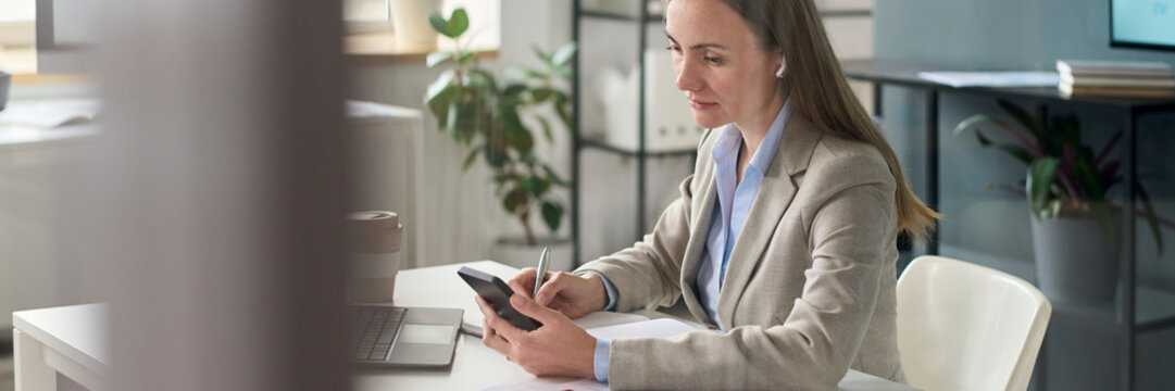 Manager working with mobile phone and documents in modern office