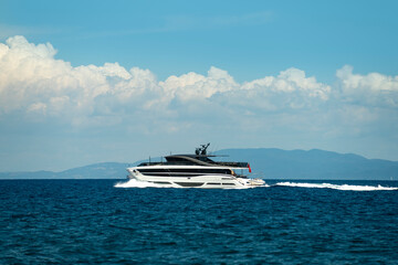 A luxury yacht sailing in the open sea with a background of withe clouds and blue sky