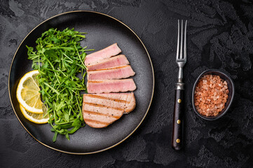 Succulent grilled tuna steak, showcasing vibrant color and rich taste, perfect for summer barbecues and elegant dinners. black background. top view