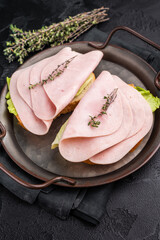Delicious ham sandwich stacked high with fresh veggies, perfect for a quick lunch or picnic delight. black background. top view