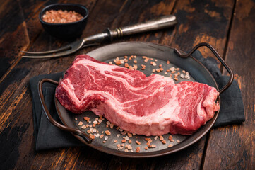 Prime Raw Chuck eye roll steak, fresh beef meat in steel tray. wooden background. top view