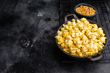 Delicious cheese and salted popcorn in a skillet . black background. top view