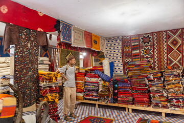 Traveler exploring Moroccan rug shop with colorful traditional textiles