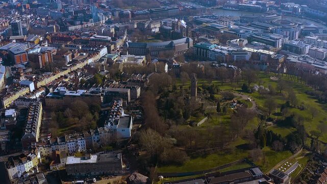 4K drone view of Bristol&rsquo;s Brandon Hill : Cabot Tower rises above winter trees, Georgian terraces and the modern Harbourside waterfront - dynamic blend of green parkland and bustling cityscape.