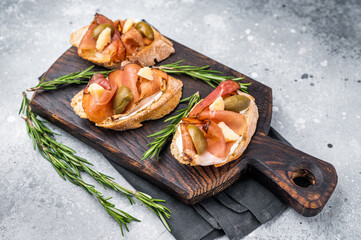 Tapa with Jamon cured ham, parmesan cheese and olives. grey background. top view