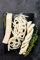 Assortiment of Traditional Caucasian Chechil white cheese on black board, top view.