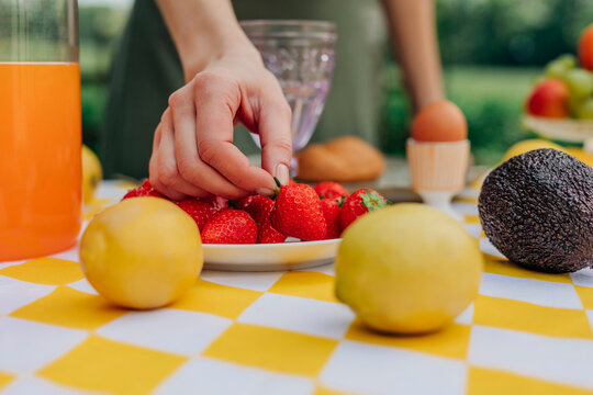 Woman picking fresh strawberries during outdoor summer breakfast