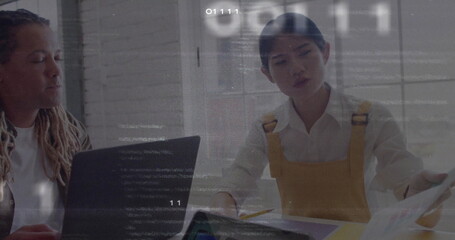 Colleagues reviewing printed documents and laptop in meeting room wearing mustard yellow overalls