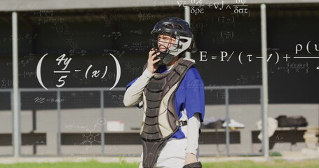 Standing catcher wearing blue jersey and chest protector on grass by dugout, with math formulas