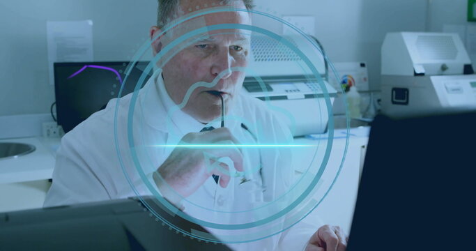 Studying scientist wearing coat and tie holding eyeglasses in lab with computer monitor and printer