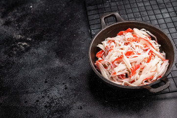 japanese Crab meat, crabmeat imitation in a skillet. black background. top view