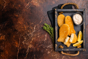 Crusted Fish sticks fingers with lemon and tartar sauce in wooden tray. brown background. top view