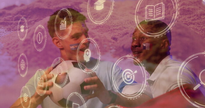 Standing two men wearing polo shirts in studio, holding soccer balls with digital icons