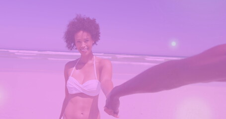 Reaching smiling woman extending her hand at sandy beach, with white bikini top and ocean waves