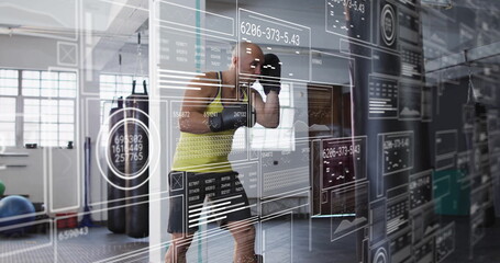 Performing shadow boxing drills male athlete in neon top and gloves in gym, with digital overlay