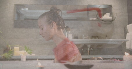 Soaking woman relaxing in spa-like bathroom, with lit candles, folded towels and circular mirror