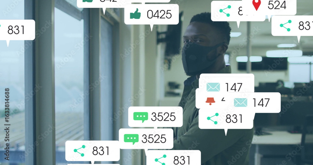 Poster standing masked man checking floating notification icons by window, monitors in office, copy space