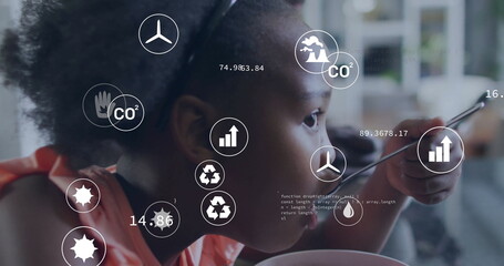 Eating girl analyzing environmental icons at home dining area, with spoon bowl digital overlay