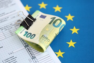 European euro currency money notes bunch on tax form and European union blue flag close up