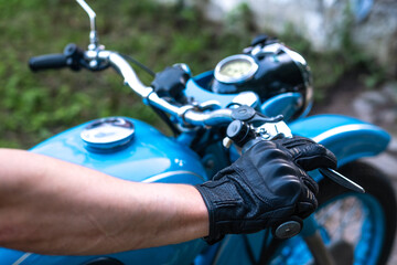 A motorcyclist holds the handlebars of a motorcycle in a motorcycle glove
