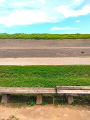 真夏の江戸川河川敷のサッカー場のベンチと砂利道のある風景
