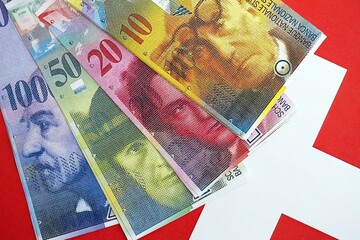 Swiss franc banknotes and flag. The current francs money bills lies on flag in big amount