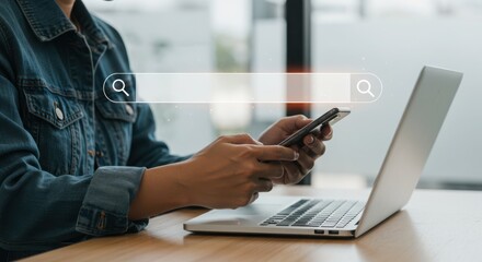 A person using a smartphone and laptop to search for information online, representing modern technology and digital connectivity in everyday life