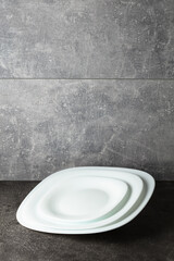 Empty white plates on a grey stone background.