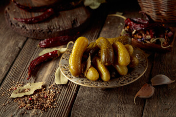 Pickled cucumbers with ingredients on an old wooden table.