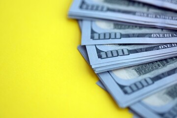 Big amount of United States hundred dollar bills on yellow background