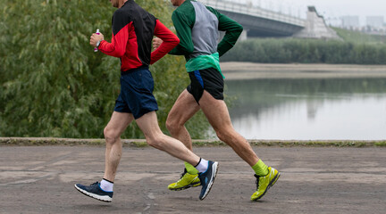 two older runners running in river embankment marathon race