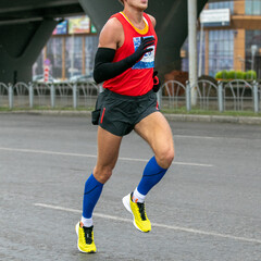 runner athlete in compression socks and long sleeve running marathon in cold weather