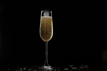 Sparkling champagne in a tall flute glass, filled with effervescent bubbles, against a dramatic dark background with light reflections and subtle liquid splashes, symbolizing celebration and luxury.