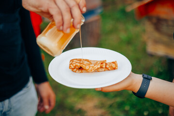 Pouring Honey Over Rolled Pancake in Outdoor Setting