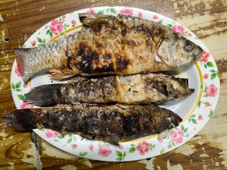 Three freshly grilled fish on a white floral plate