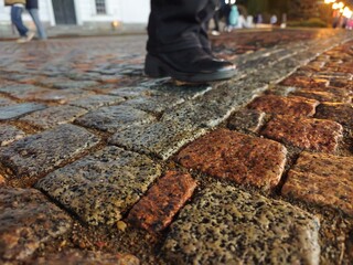 Footsteps on wet cobblestones at night, capturing reflections and textures in a quiet urban setting