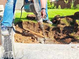 Homeowner works on outdoor renovation with power tool during sunny afternoon in a backyard garden