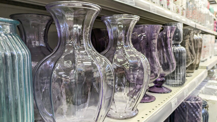 Row of decorative glass vases in various shades of purple, displayed on store shelf. Concept of home decor, interior design or retail