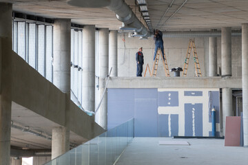 A team of workers collaborates to install a modern ventilation system within a building, carefully...