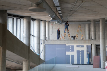 A team of workers collaborates to install a modern ventilation system within a building, carefully...